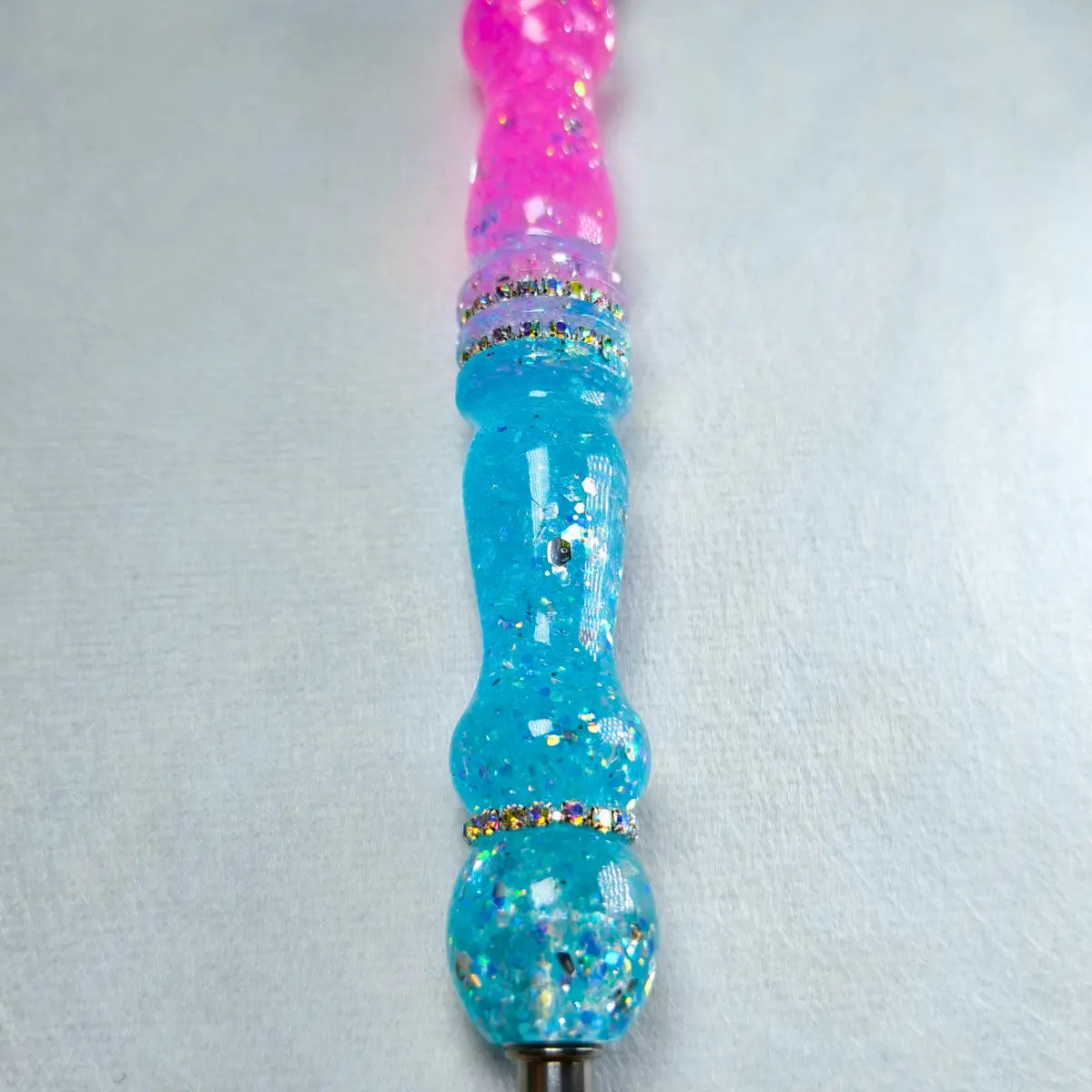 Détail des finitions pailletées roses et bleues du stylet artisanal