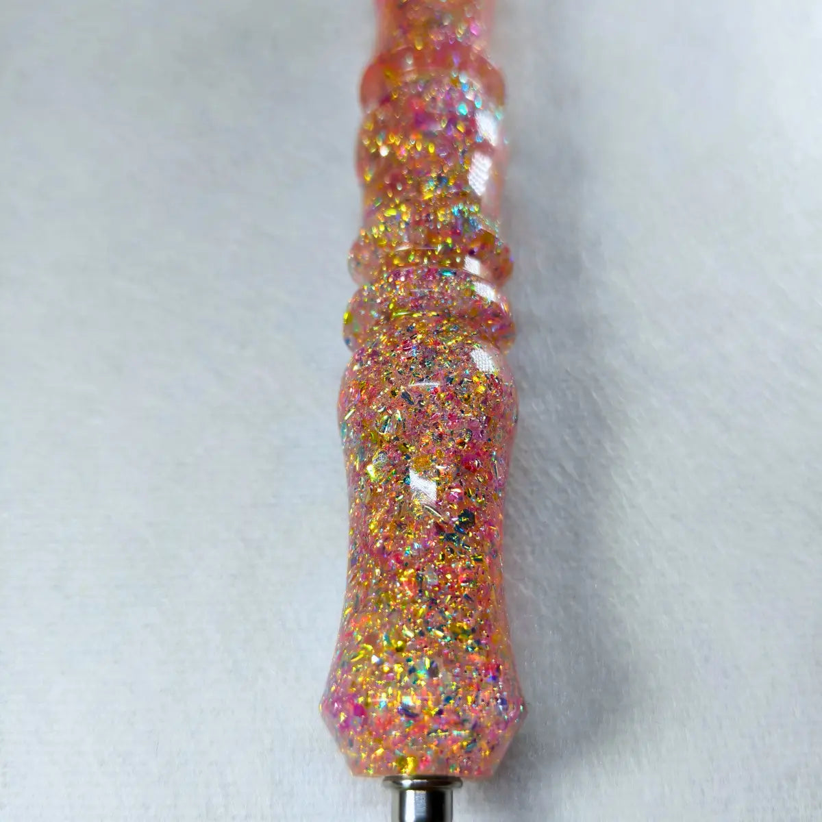 Détail des paillettes multicolores sur le manche rose doré
