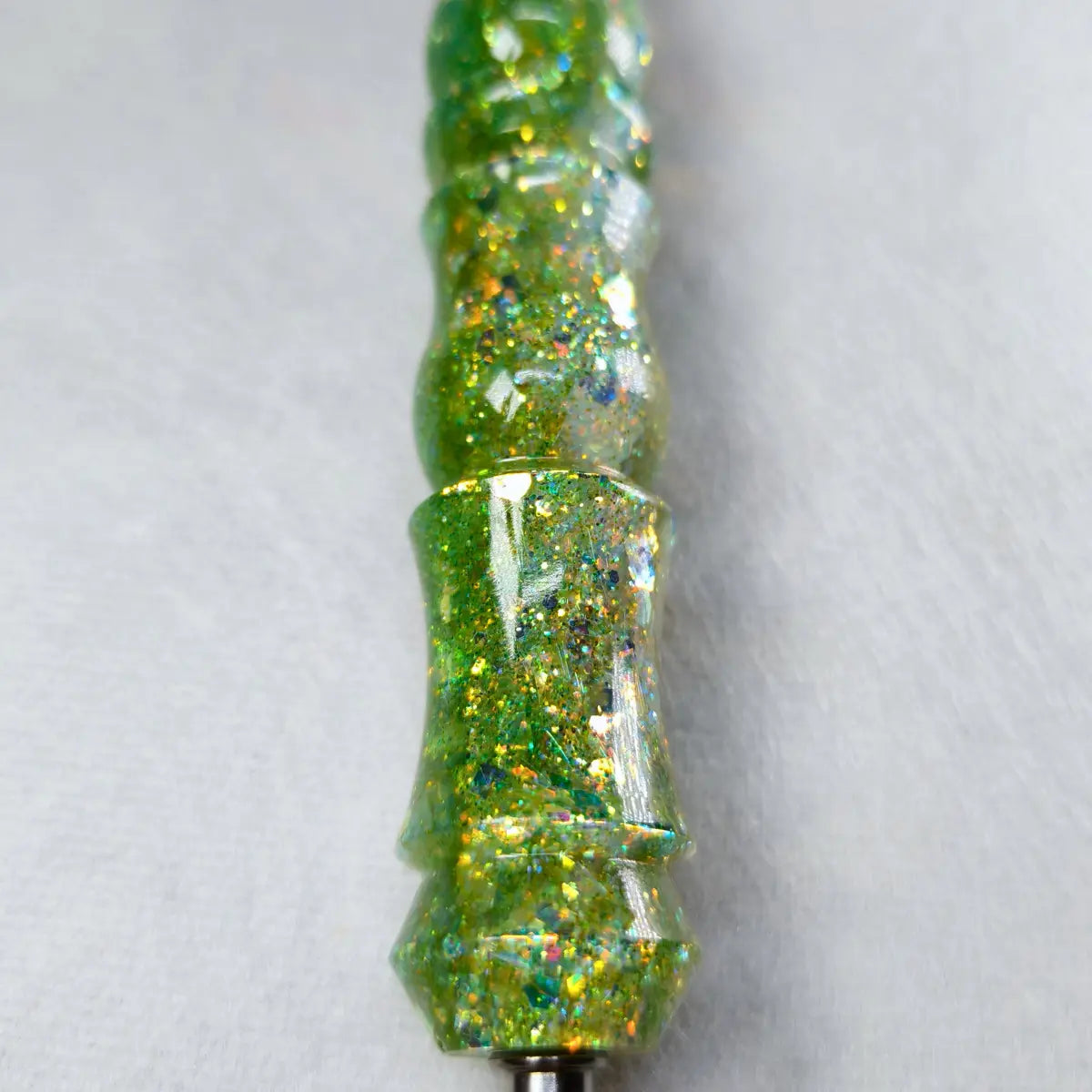 Détail des paillettes vertes et dorées sur le manche du stylet