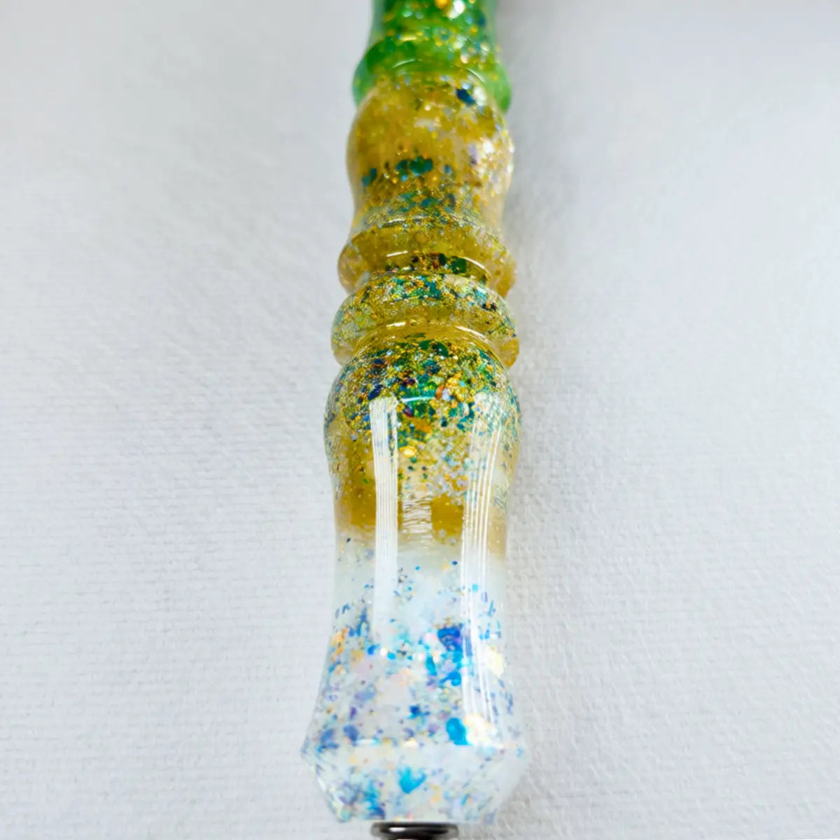 Gros plan sur le manche du stylet fait main avec un dégradé vert et or