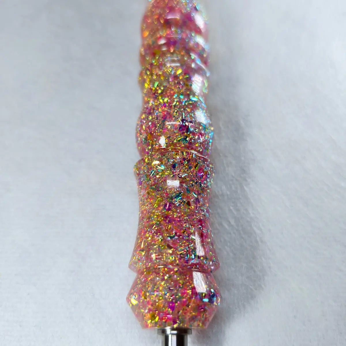 Gros plan sur le manche rose doré pailleté du stylet fait main