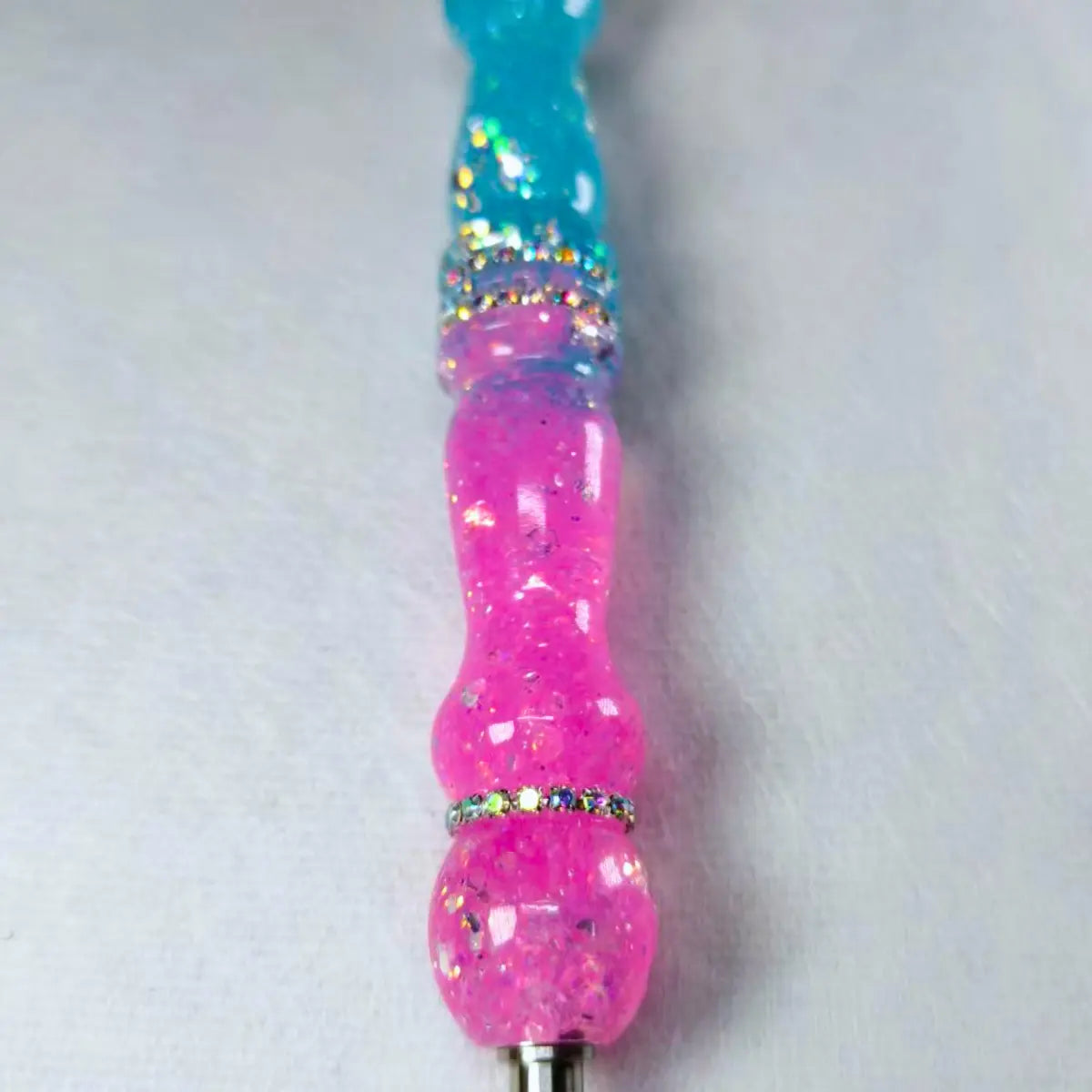 Gros plan sur le manche rose et bleu pailleté du stylet fait main