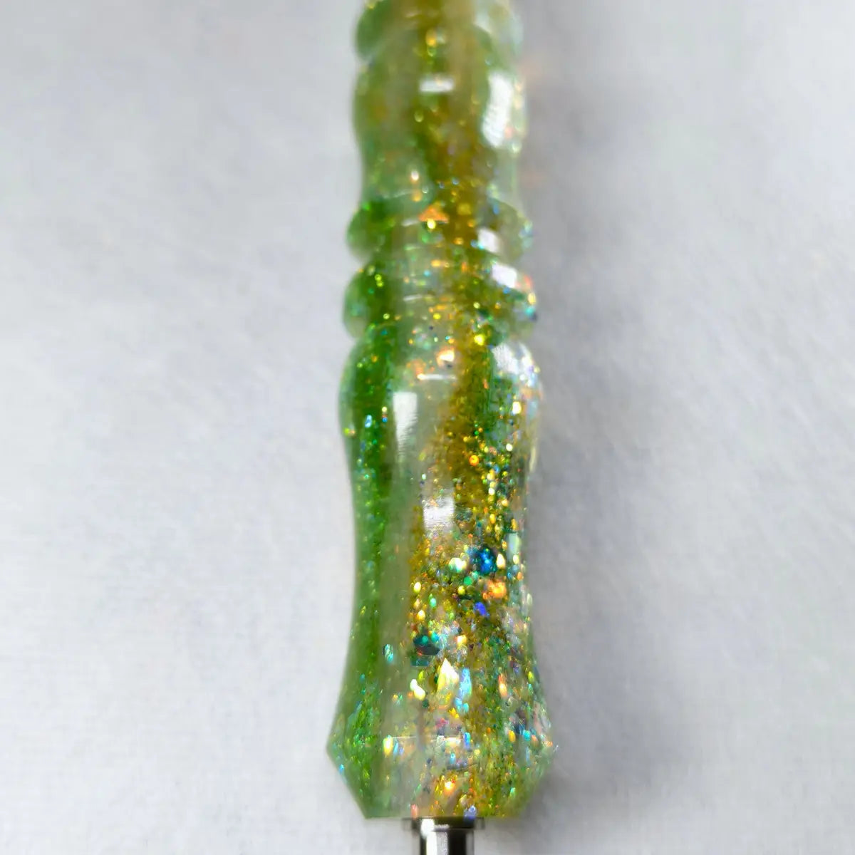 Gros plan sur le manche vert et or pailleté du stylet fait main