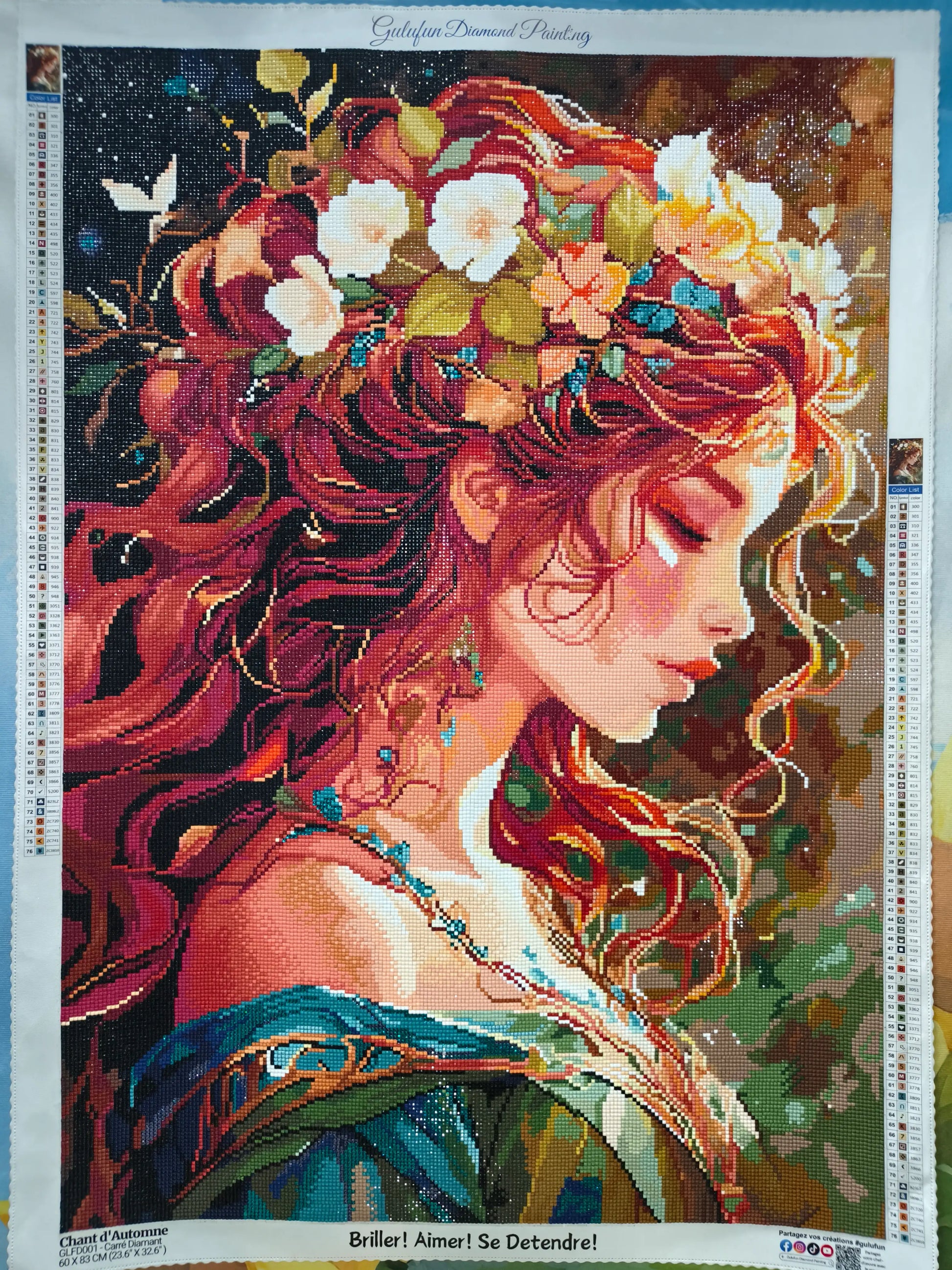 Photographie réelle du kit de broderie diamant 'Chant d'Automne' une fois terminé. On y voit le portrait de la femme rousse avec sa couronne de fleurs, ainsi que la charte de couleurs sur les bords de la toile (60x83cm).