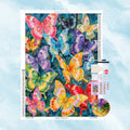 Kit de broderie diamant représentant de multiples papillons aux couleurs vives sur un fond bleu texturé.