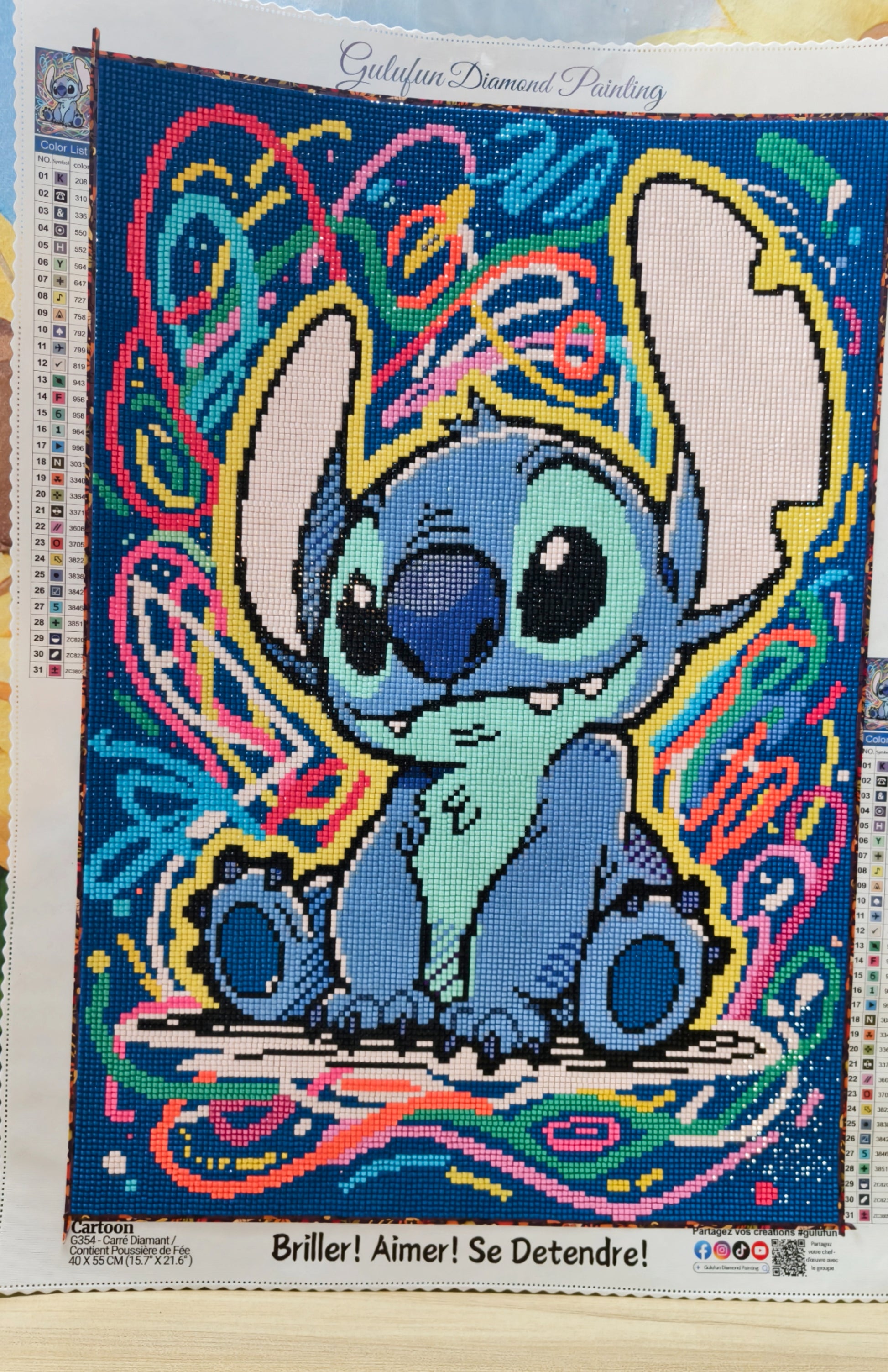 Broderie diamant Stitch coloré terminée, personnage Disney assis sur fond graphique multicolore