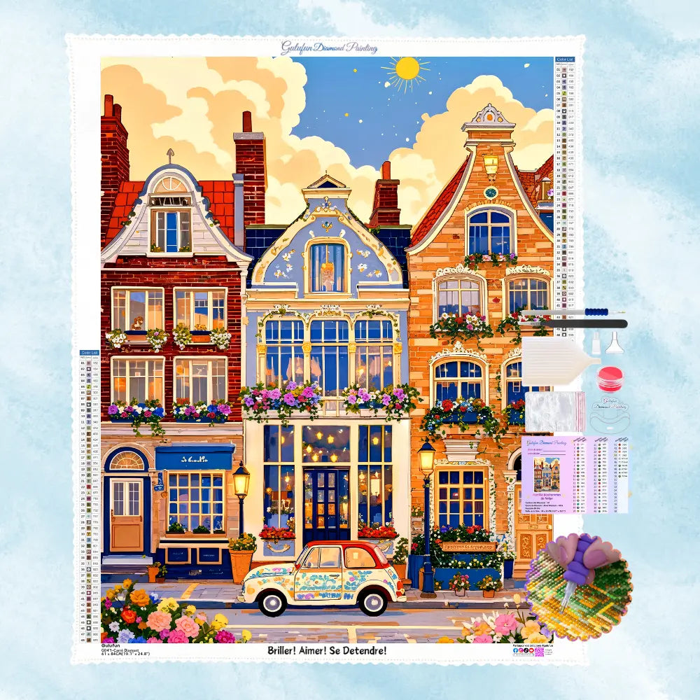 Vue d'ensemble du contenu du kit de broderie diamant 'Rêve Urbain' : la toile adhésive imprimée du motif de maisons colorées, les sachets de strass carrés ou ronds, le stylet, la colle et le plateau de tri.