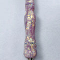 Macro sur les éclats dorés et nacrés encapsulés dans la résine satinée violette au-dessus de l'anneau de strass.   