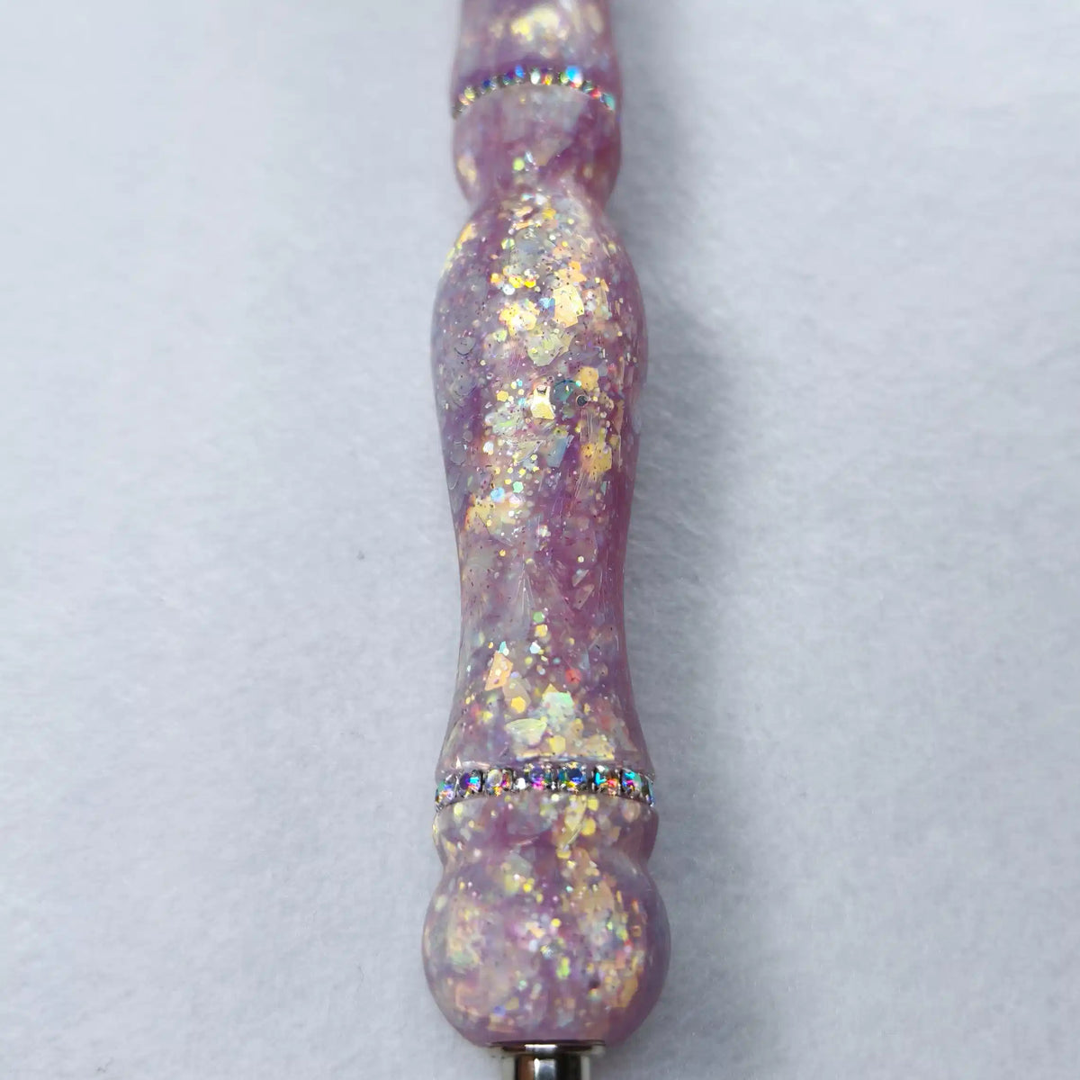 Macro sur les éclats dorés et nacrés encapsulés dans la résine satinée violette au-dessus de l'anneau de strass.   