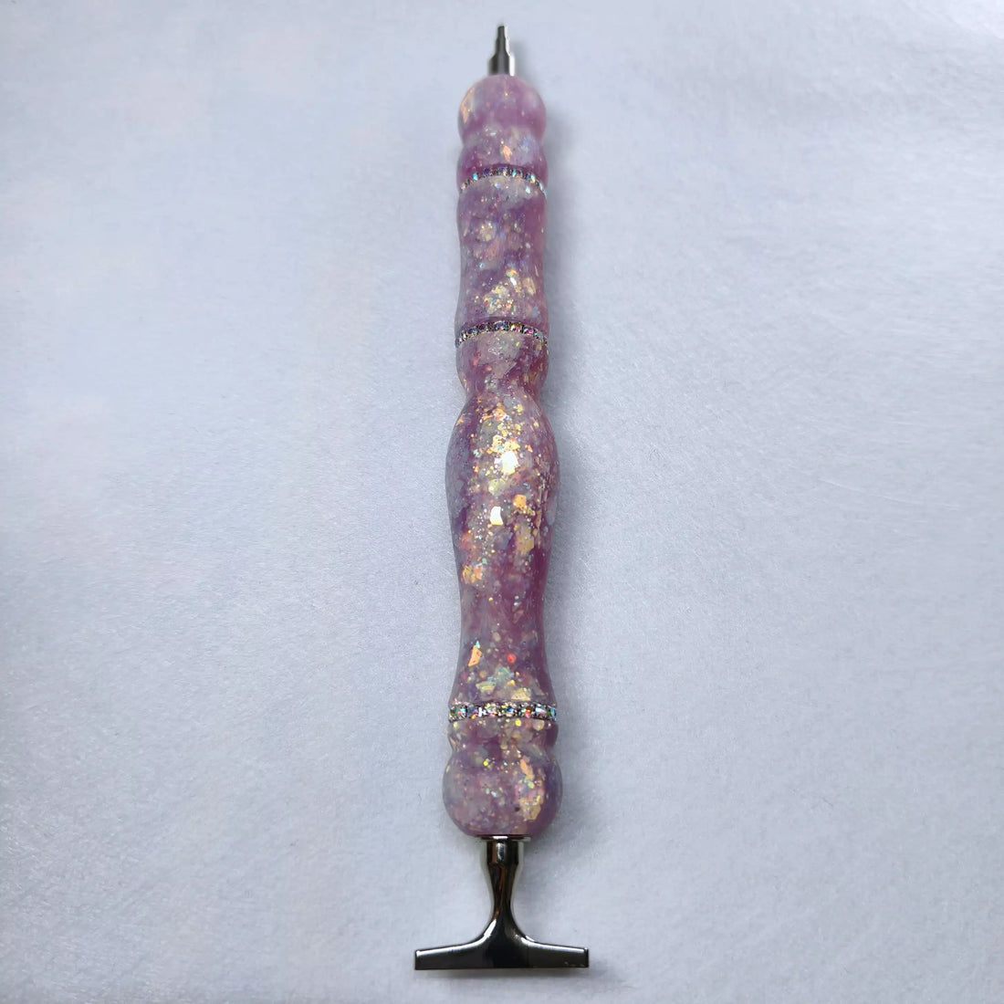 Stylo artisanal en résine mauve lilas à finition satinée orné d'anneaux de strass brillants et de reflets dorés.