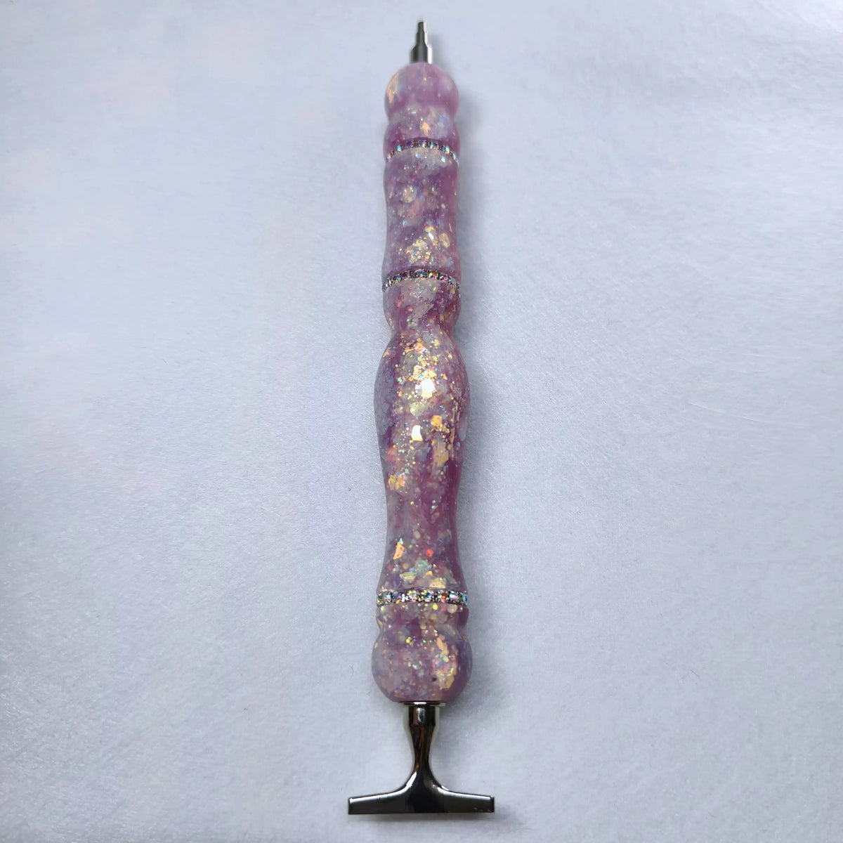 Stylo artisanal en résine mauve lilas à finition satinée orné d'anneaux de strass brillants et de reflets dorés.