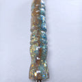 Gros plan sur la résine brillante du stylo Lagune Dorée montrant le dégradé sable chaud et bleu lagon incrusté de paillettes scintillantes.